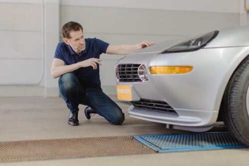 Mitarbeiter schaut sich die Front von einem alten Porsche an