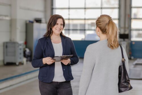 Zwei Frauen in einer Autowerkstatt bei einem Kundengespräch
